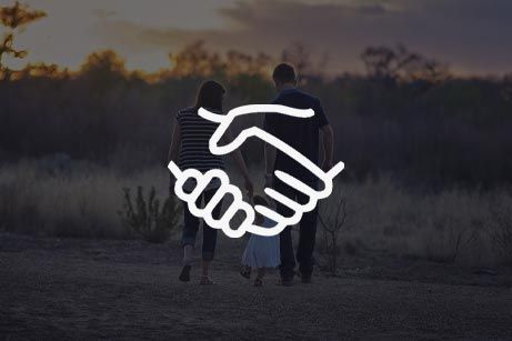 A family is shaking hands while walking in a field.
