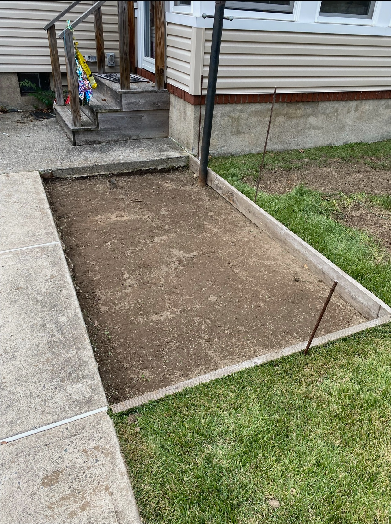 A concrete walkway is being built in front of a house.