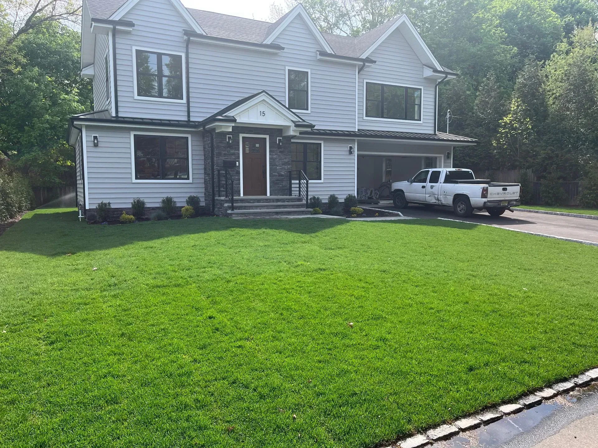 Two-story gray house with green lawn and a pickup truck in the driveway.