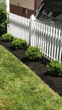 A white picket fence surrounds a lush green lawn.