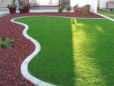 A lush green lawn with a white border and red gravel.