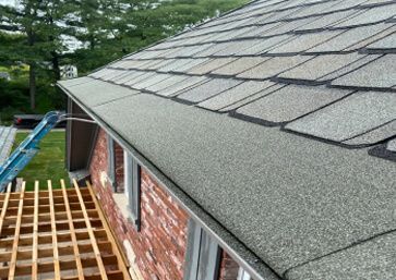 Close-up of a house roof with gray shingles with Gutter Cap.