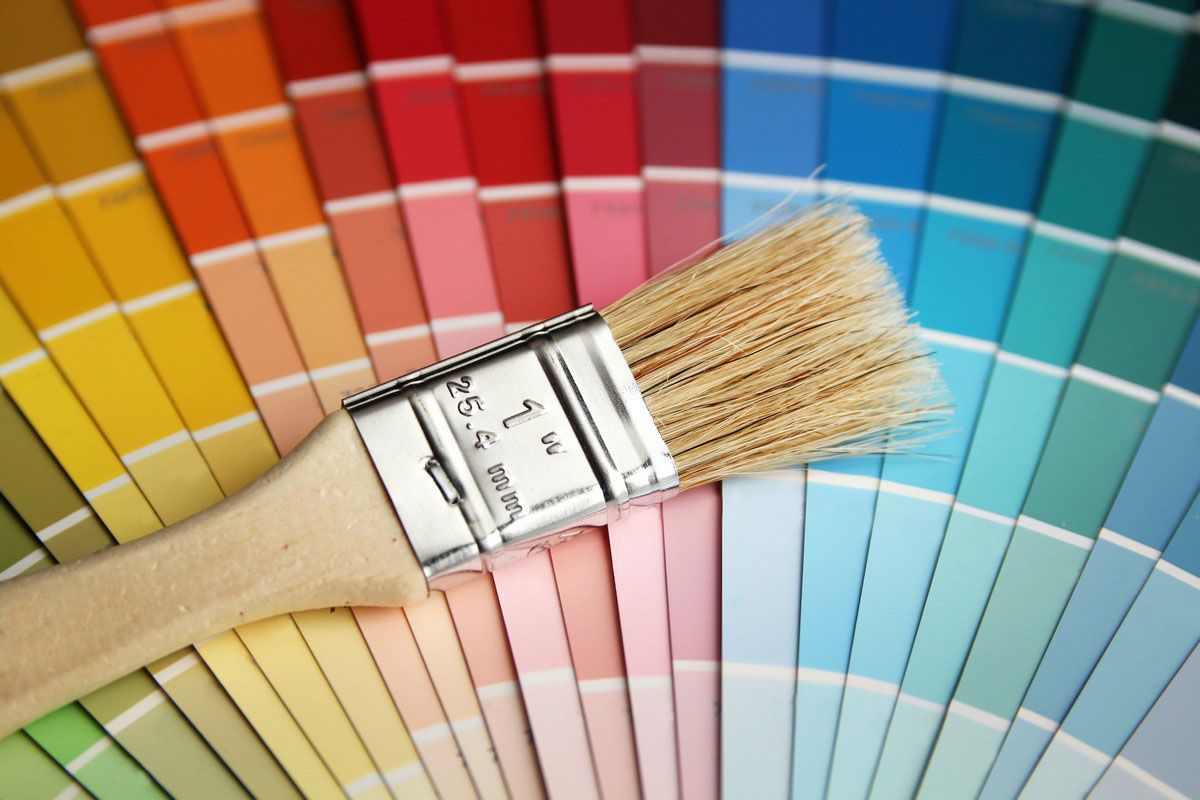 Paintbrush on a colorful fan deck of paint swatches.