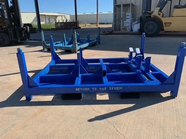 Blue metal shipping pallet with upright supports; outdoors, other pallets visible, forklift.