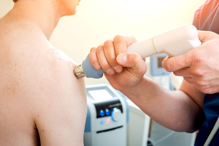 A man is getting a laser treatment on his shoulder.