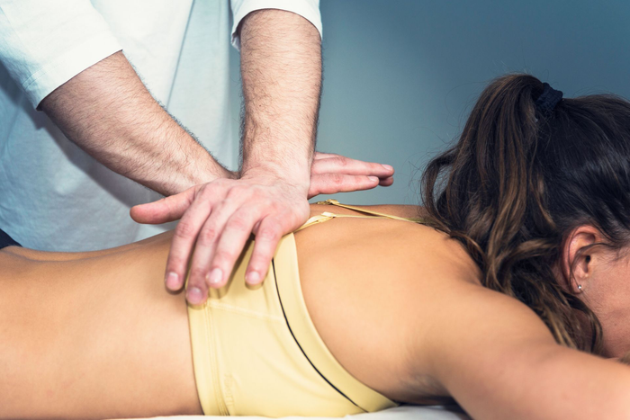 A woman is laying on a table getting a massage from a man.