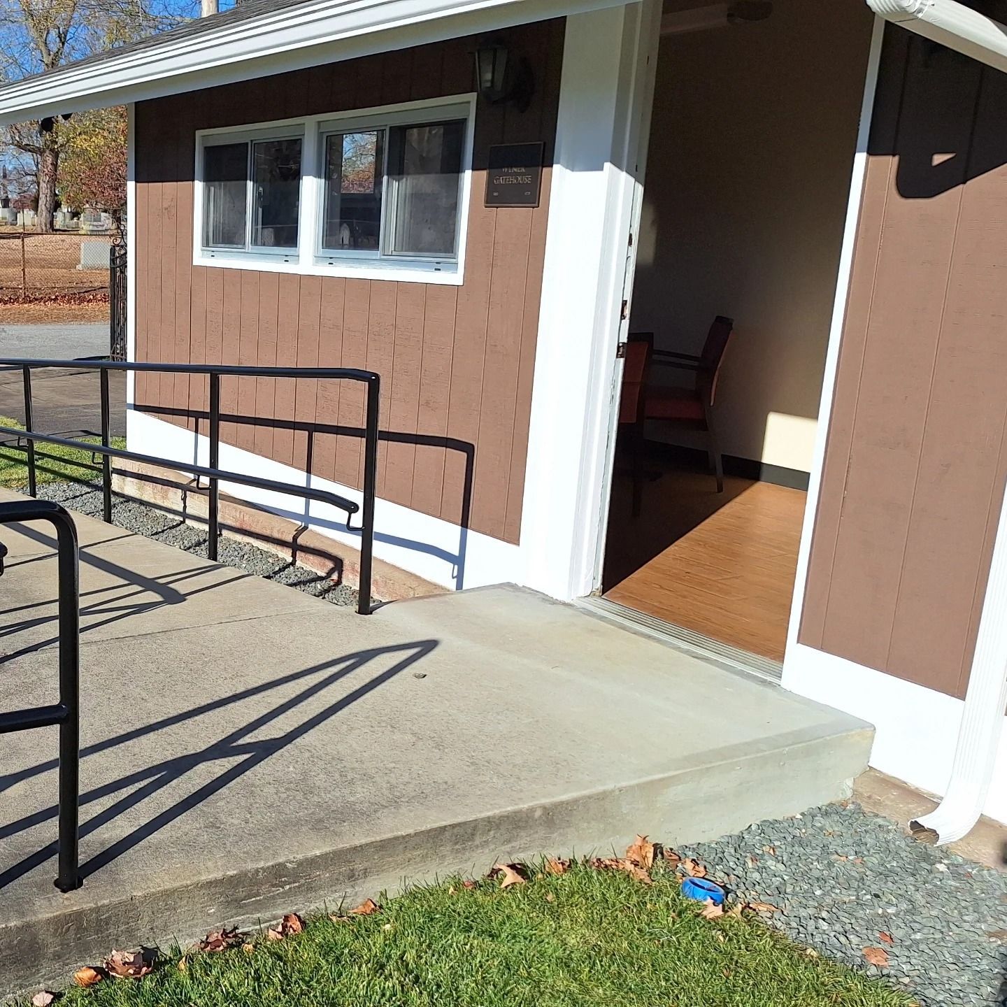 Brown building with ramp entrance and open door, possibly a public restroom.