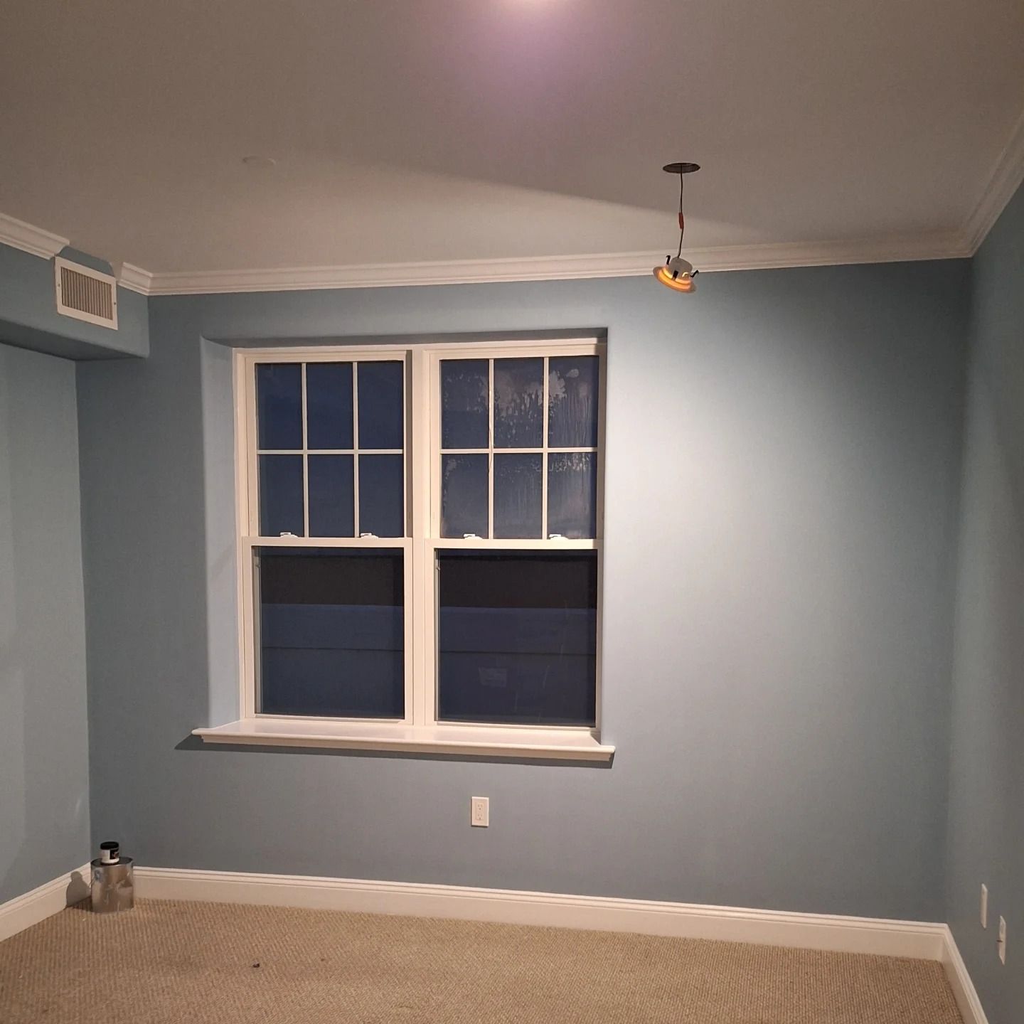 Empty room with blue walls, window, beige carpet, and a light fixture.
