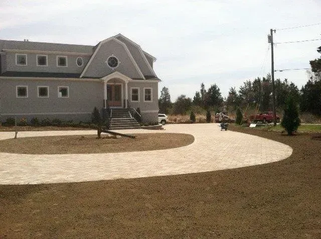 Gray house with circular driveway and landscaping.