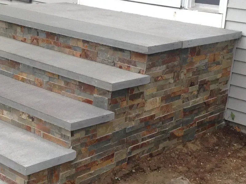 Stone steps leading up to a doorway; stone facade with gray steps and trim.