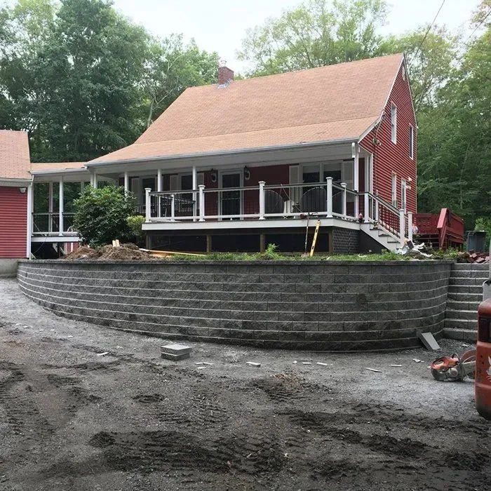 Red house with a porch and retaining wall under construction.