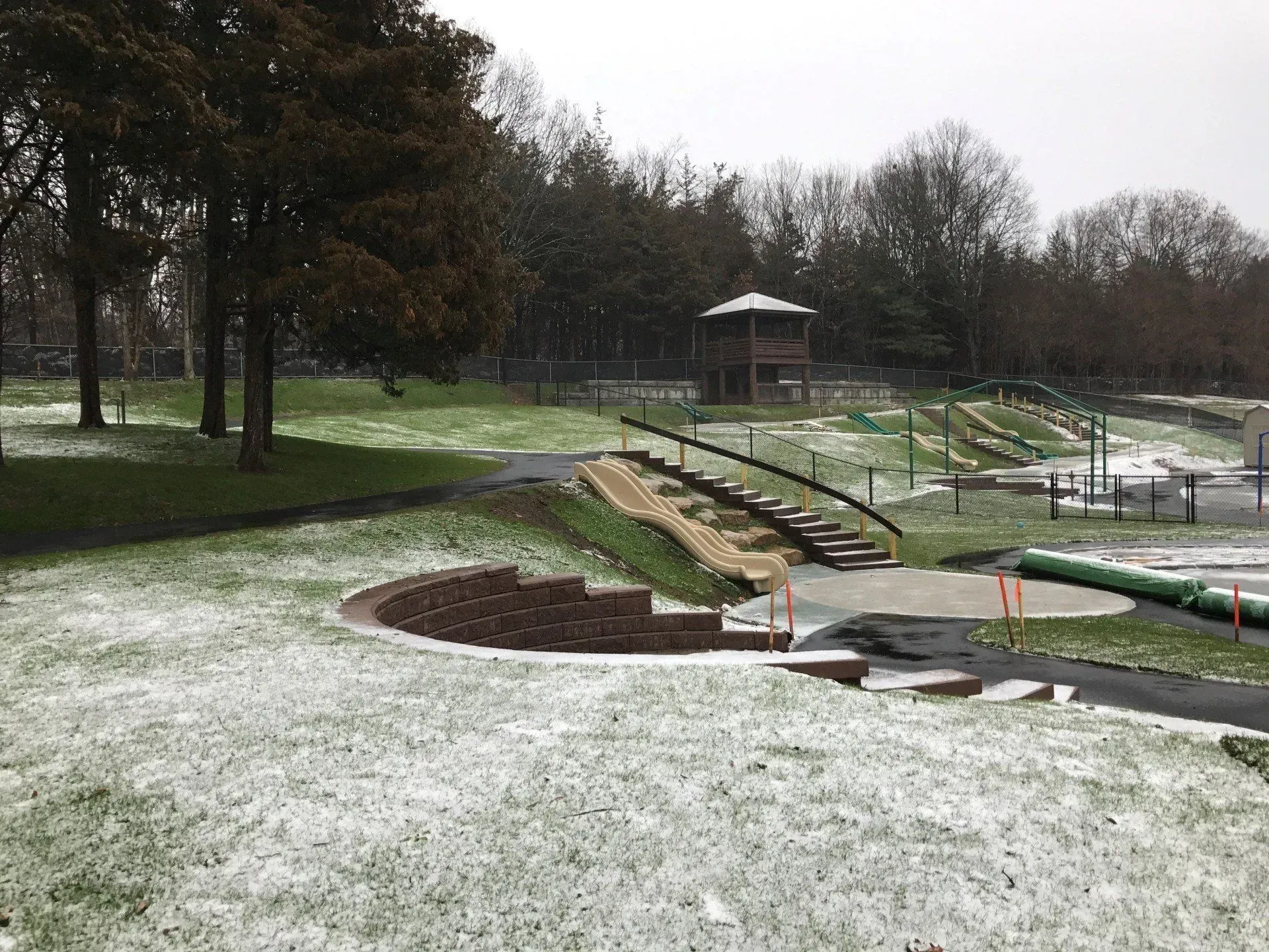 Snowy outdoor playground with wooden structures and equipment.