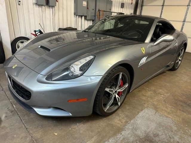 Silver Ferrari coupe parked in a garage with red brake calipers and black rims.