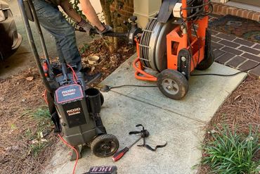 Learn More About Leak Repair Plumber performing sewer line cleaning and inspection with RIDGID drain snake equipment at a residential property.