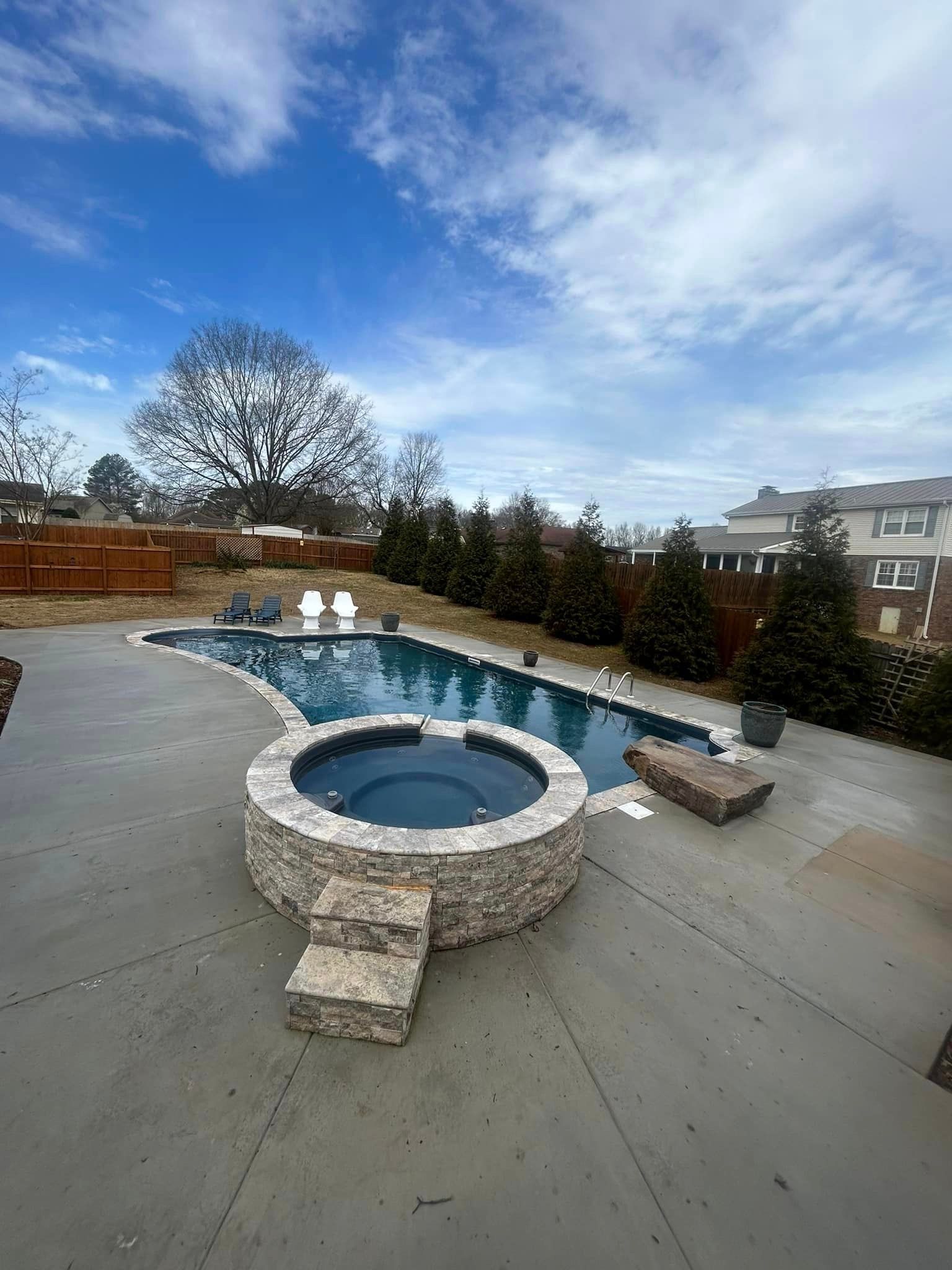 A large swimming pool with a hot tub in the middle of it.