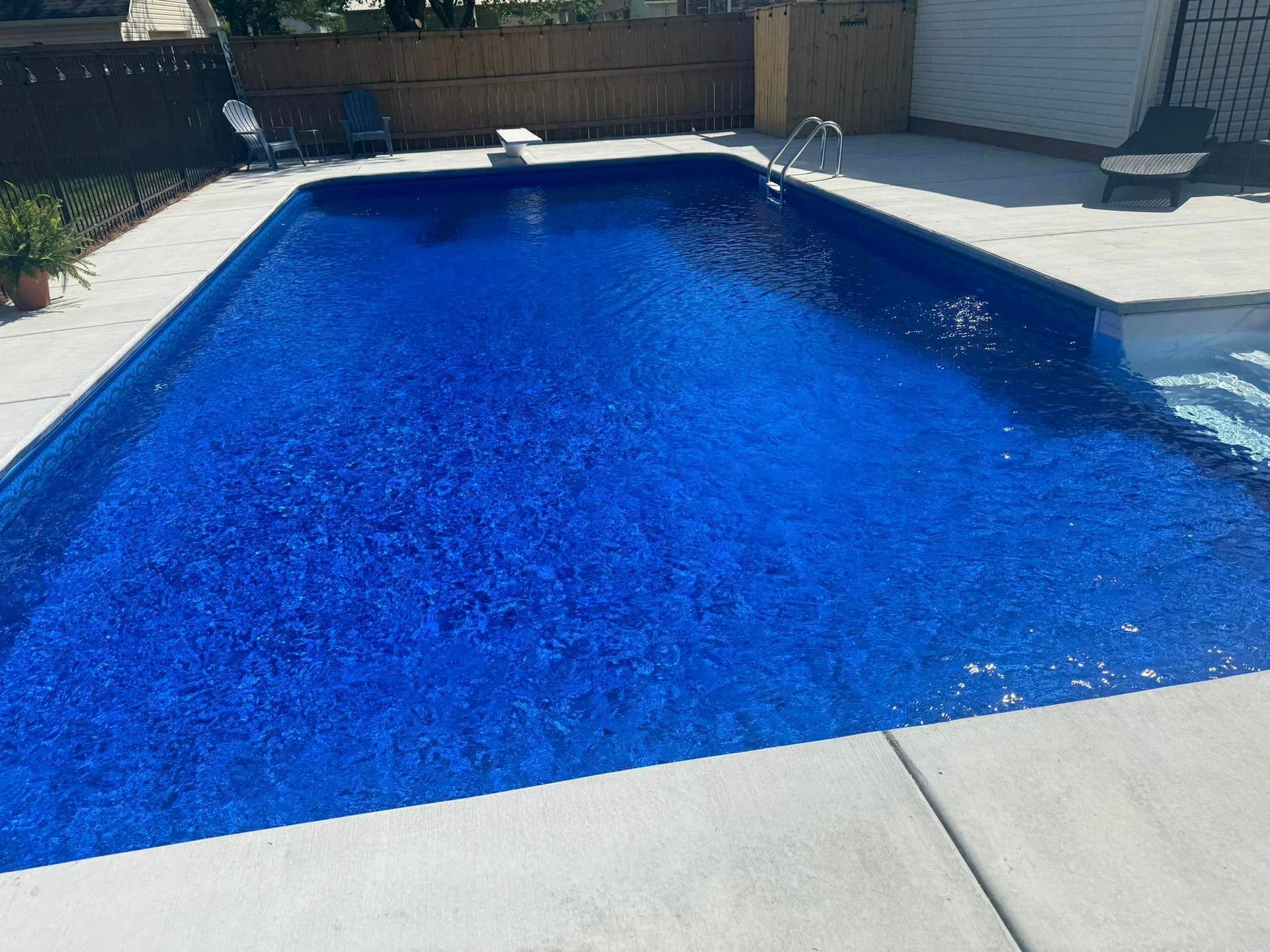 A large blue swimming pool is sitting on top of a concrete patio.