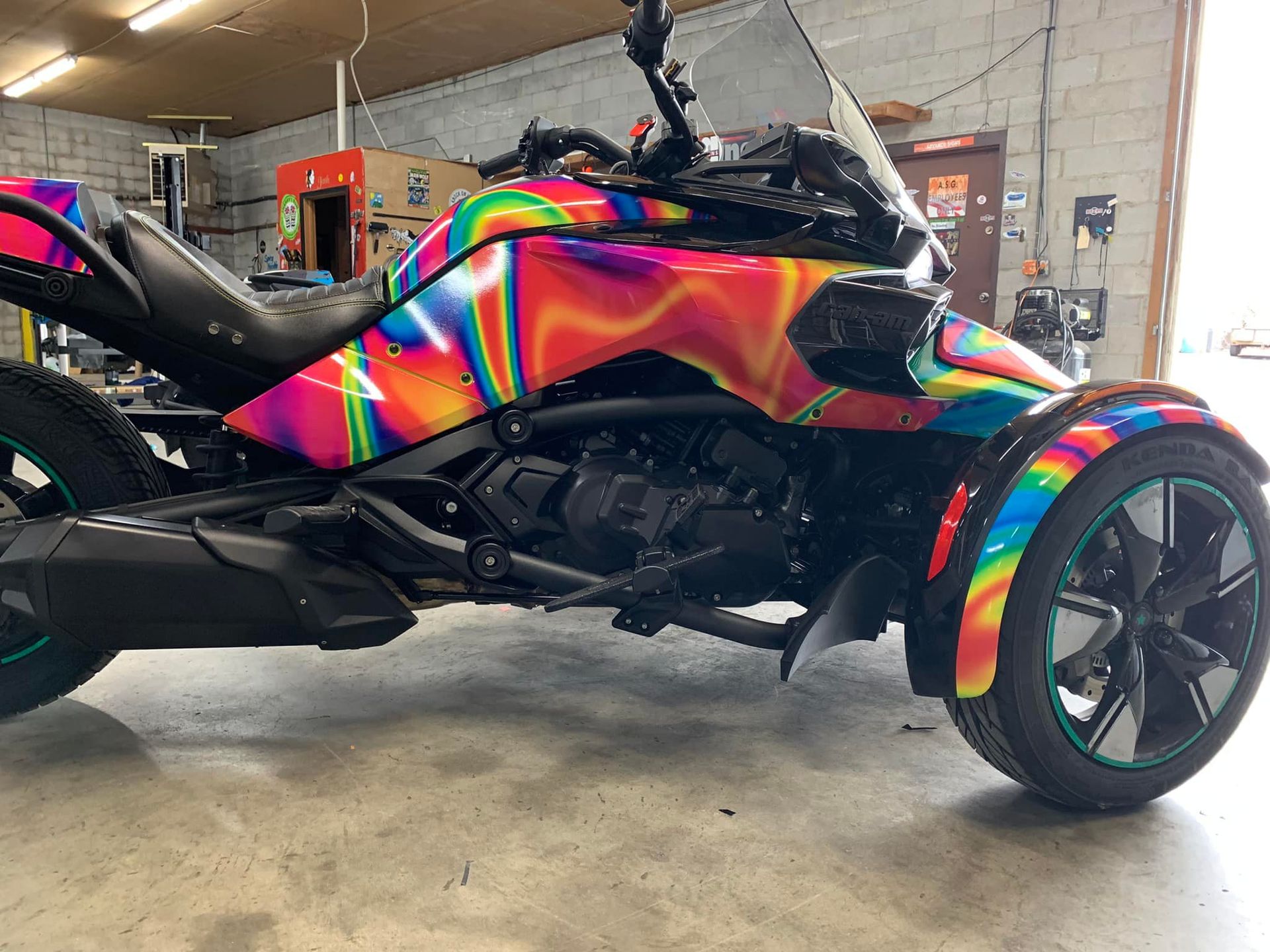 A colorful three wheeled motorcycle is parked in a garage.