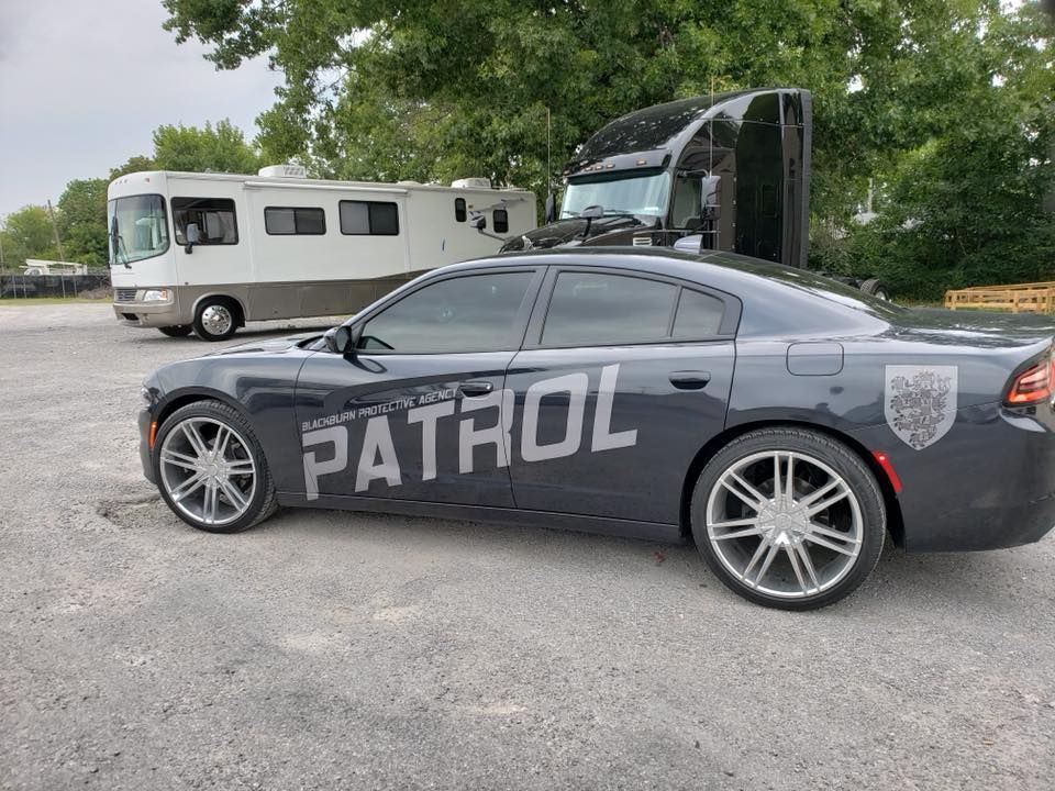 A patrol car is parked in a parking lot next to a rv.