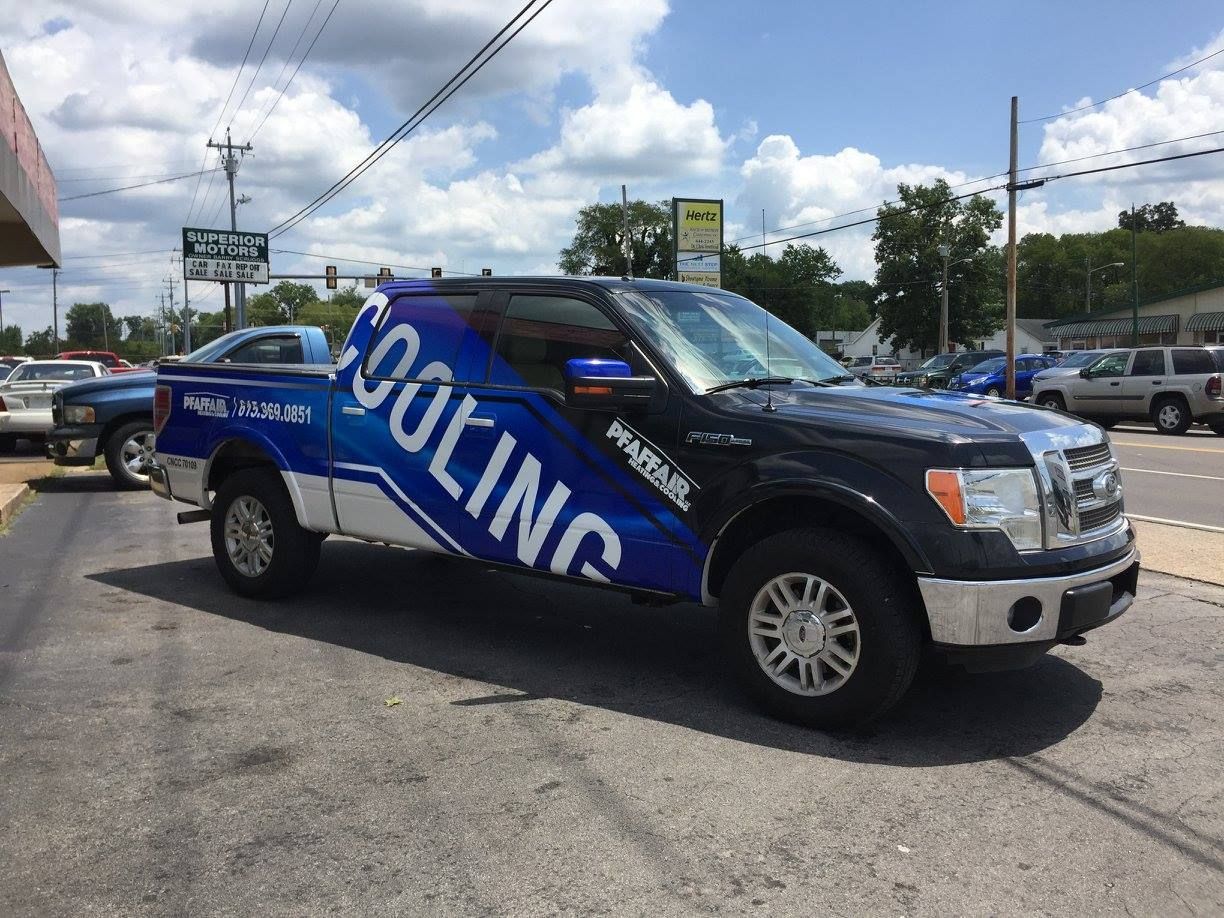 A blue and white truck with the word cooling on the side is parked on the side of the road.