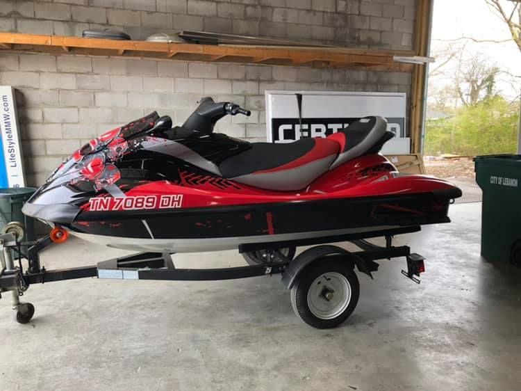 A red jet ski is parked on a trailer in a garage