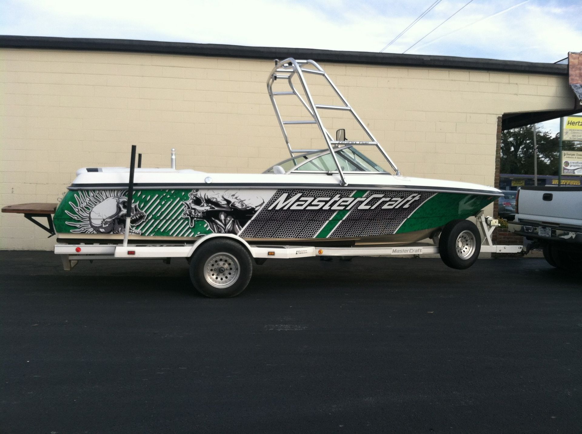 A green and white mastercraft boat on a trailer