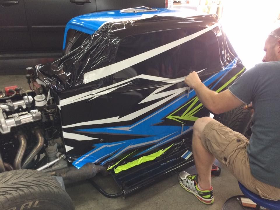 A man is wrapping a blue and black vehicle