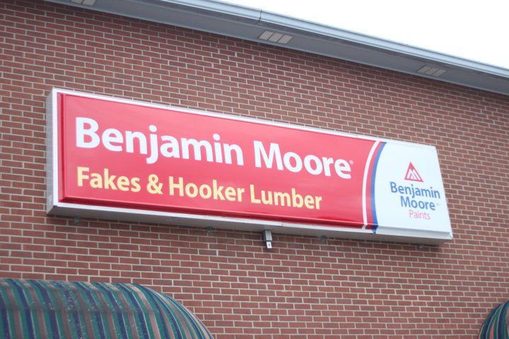 A sign for benjamin moore fakes and hooker lumber is on a brick building