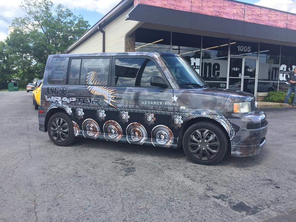 A van with a camouflage paint job is parked in front of a building.