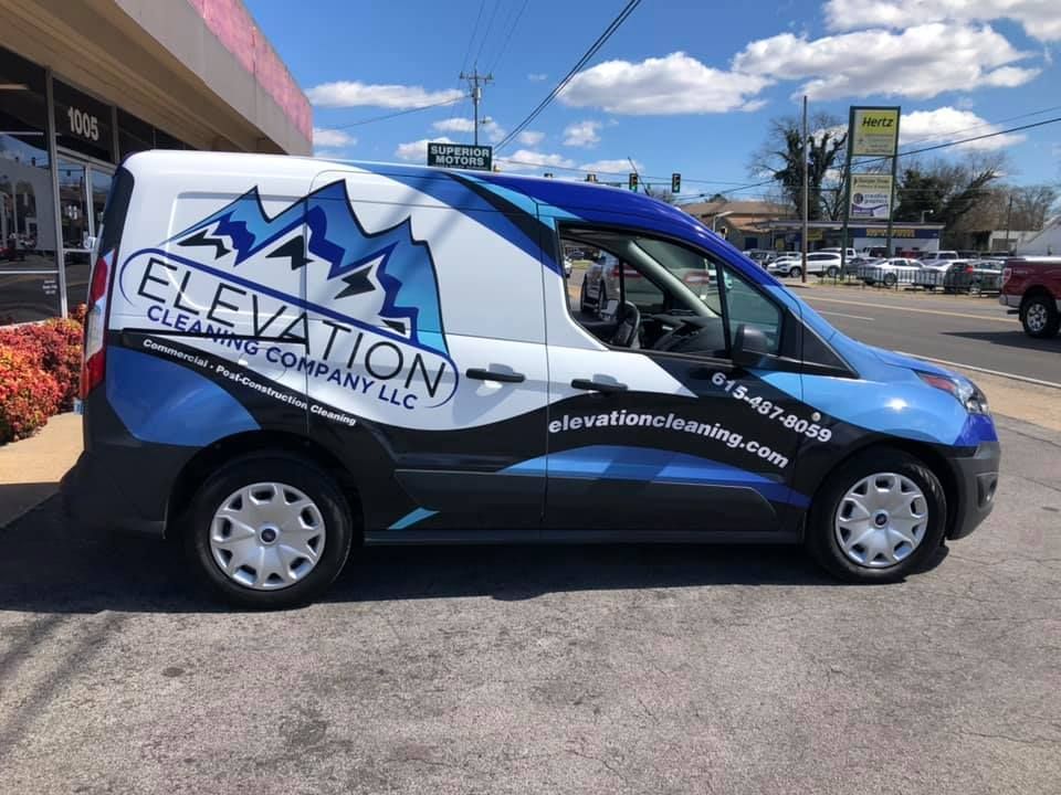 A blue and white van is parked on the side of the road.