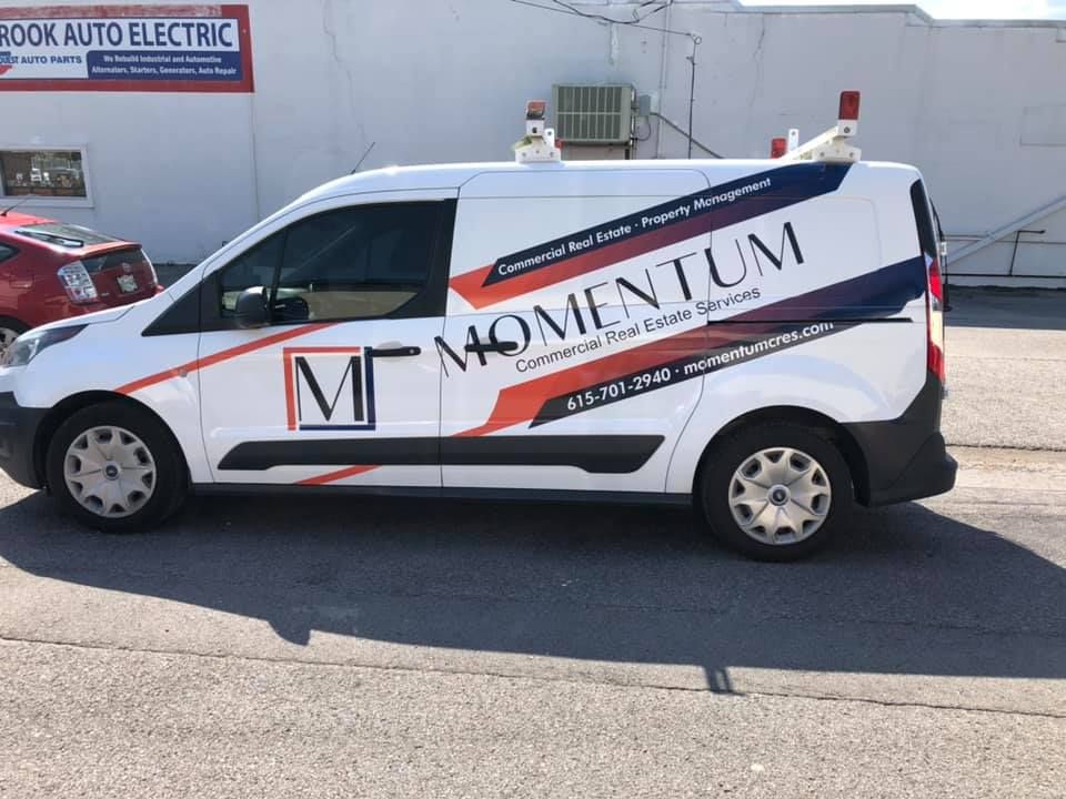 A momentum van is parked in front of a building.