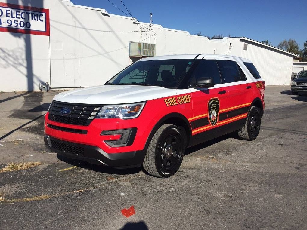 A red and white ford explorer is parked in front of a white building.
