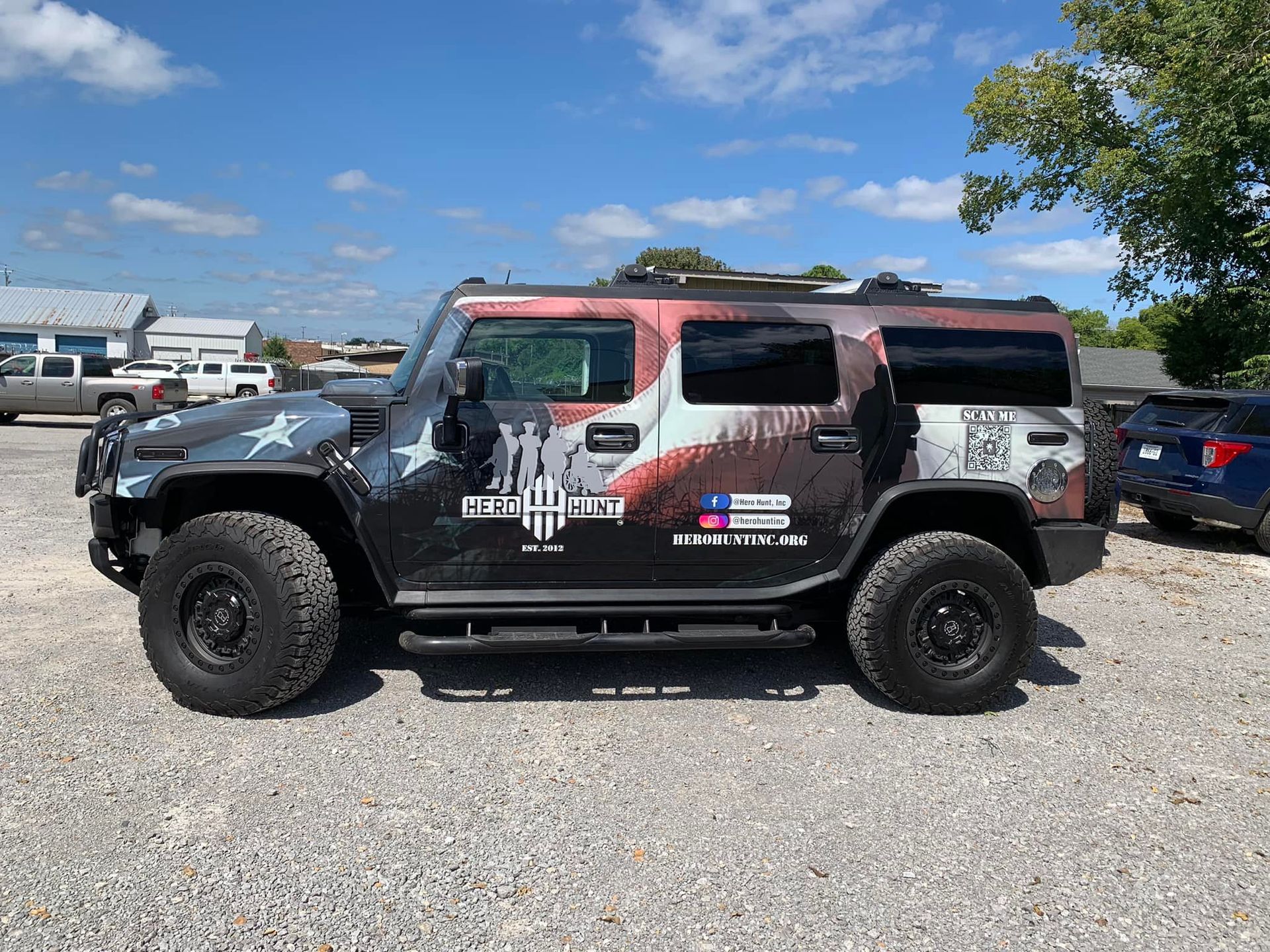 A hummer h2 is parked in a gravel lot.