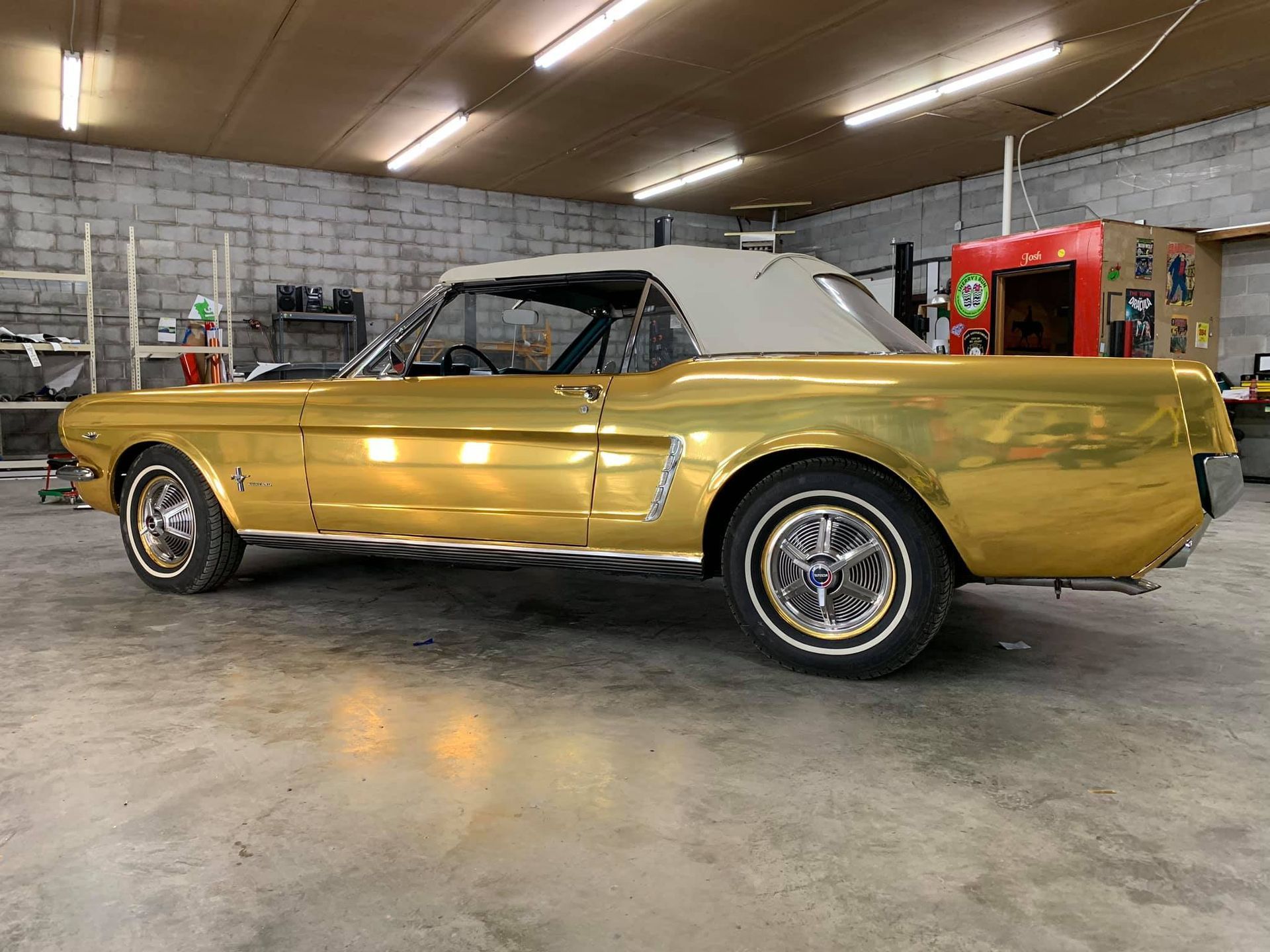 A gold mustang is parked in a garage.