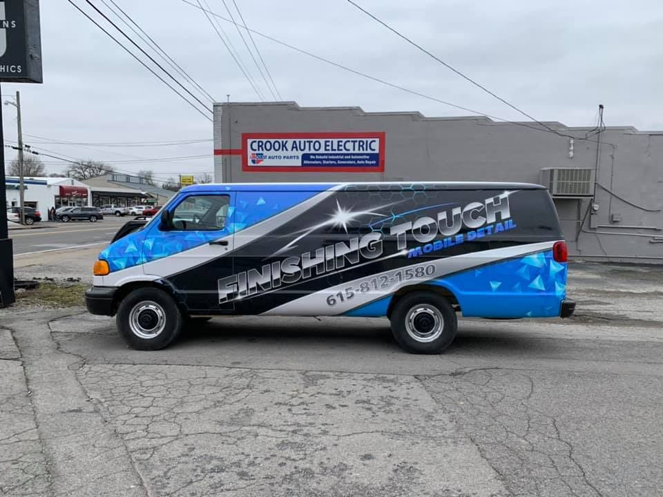 A blue and black van is parked in front of a building.