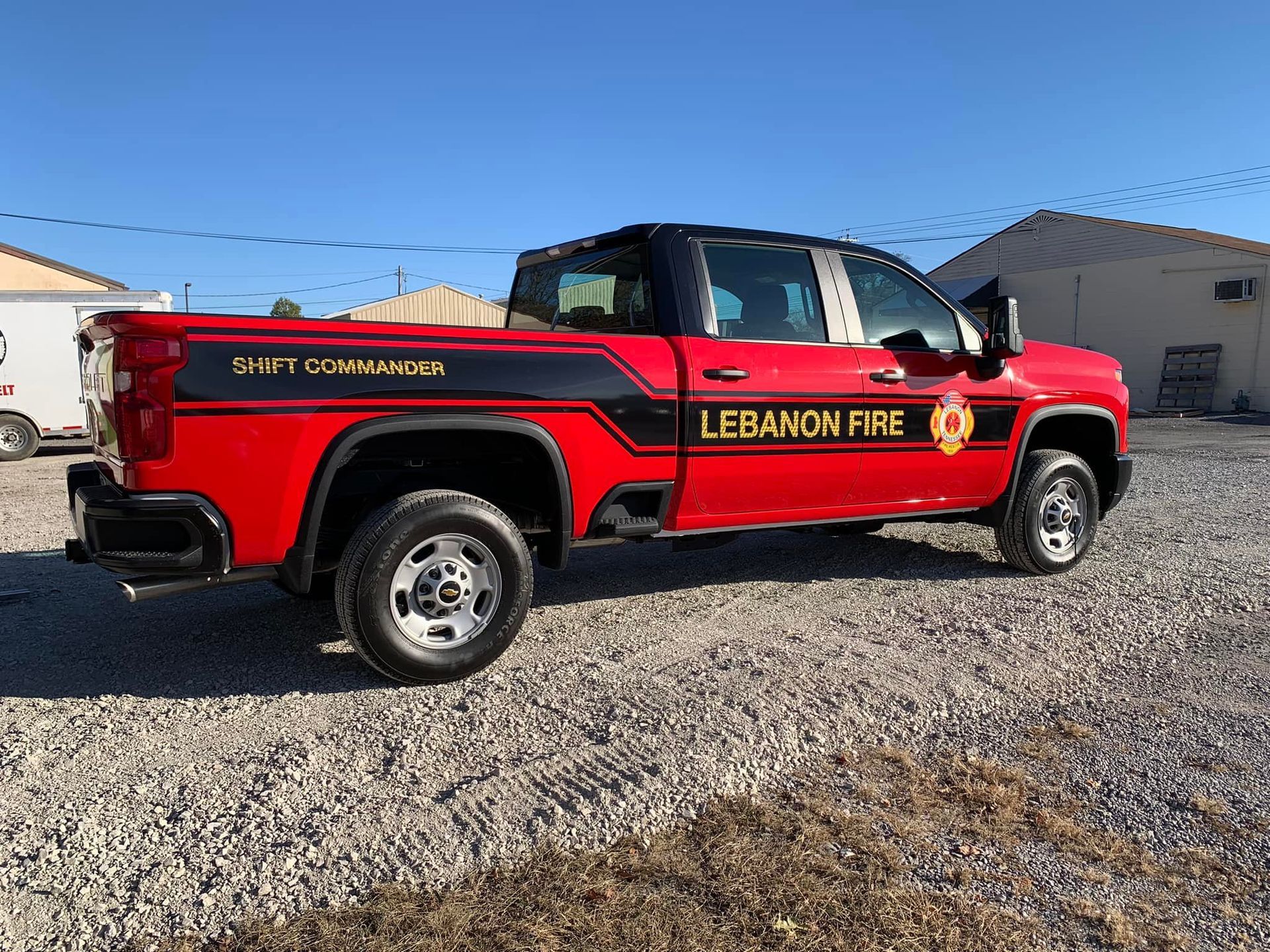 A red truck with lebanon fire written on the side is parked in a gravel lot.