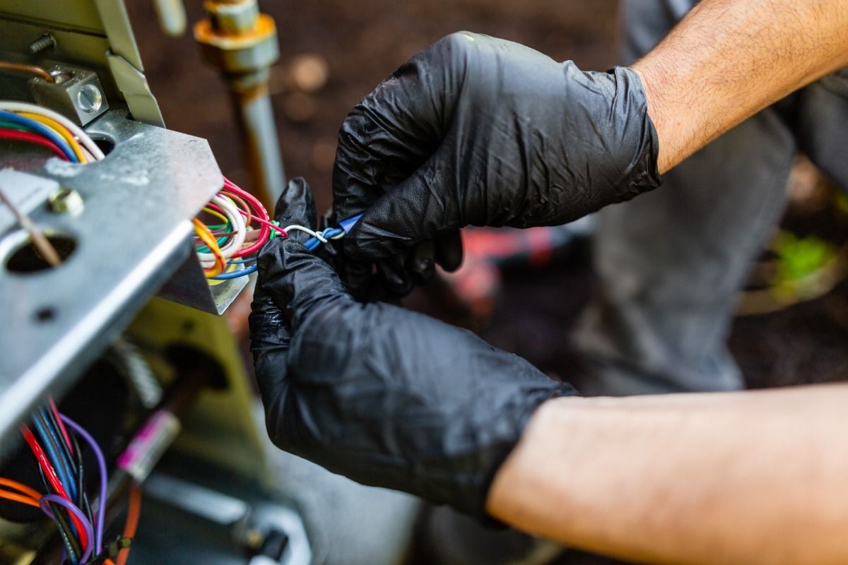 A person wearing black gloves is working on a machine.