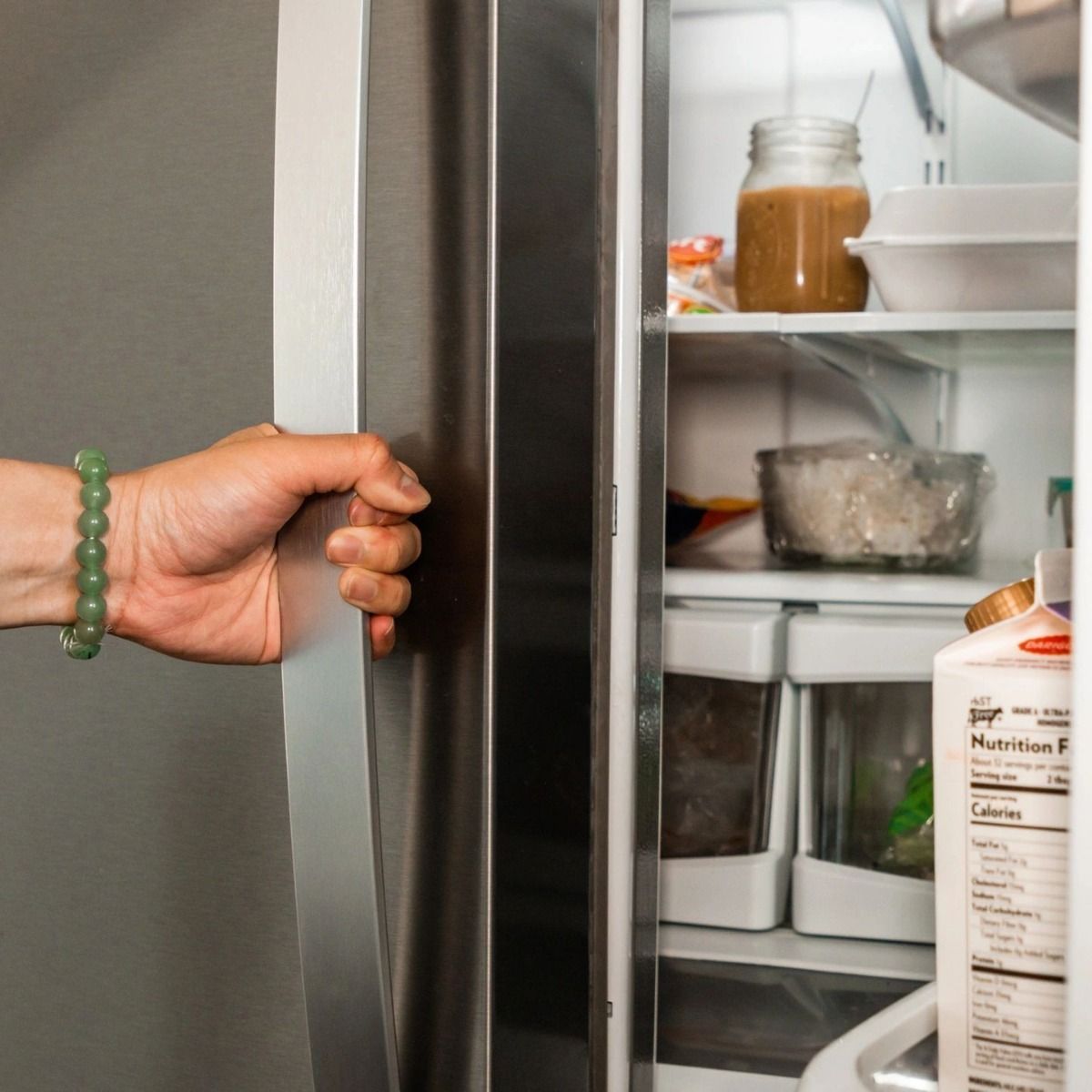 A person is opening the door of a refrigerator