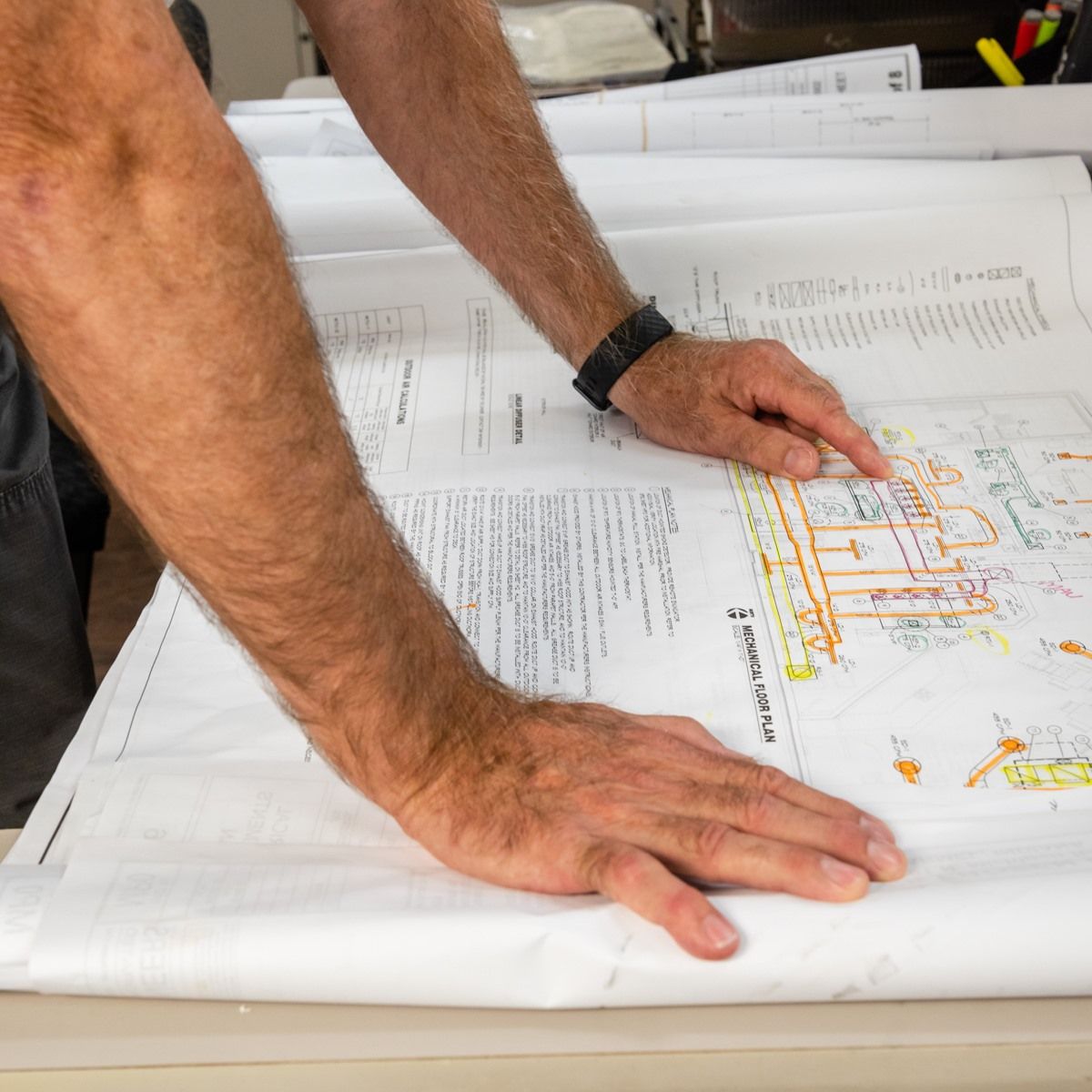 A man is looking at a blueprint on a table.