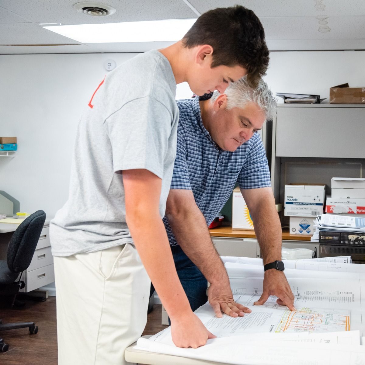 A man and a boy are looking at a blueprint together