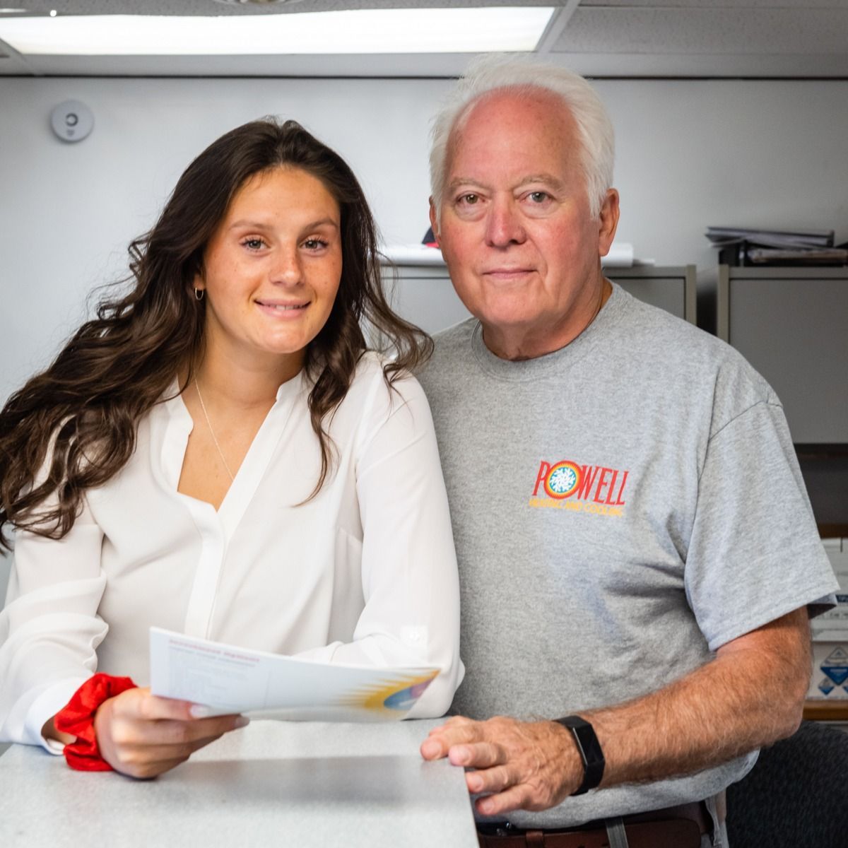 A man and a woman are posing for a picture and the man is wearing a shirt that says powell