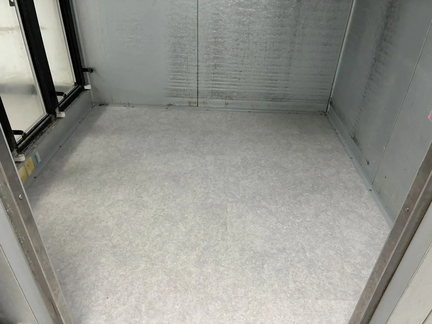 Empty gray cargo interior with textured floor and metal walls.