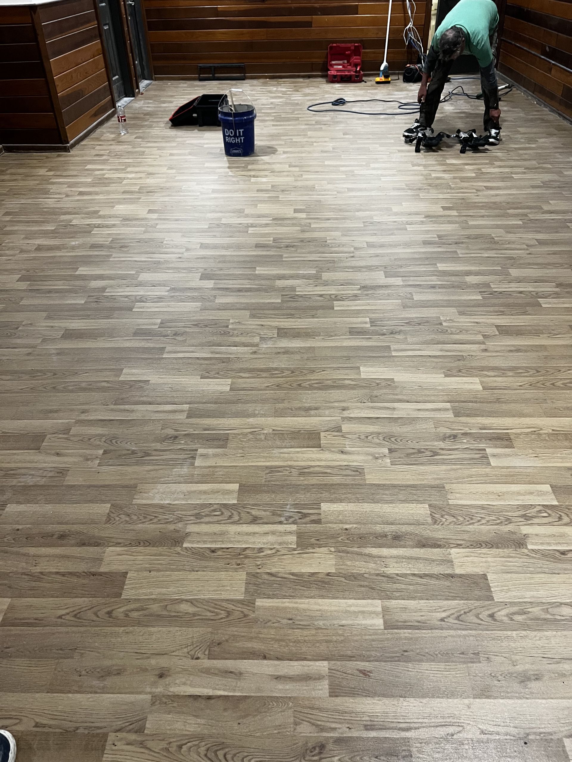 Person cleaning the floor in a room with cabinets, bucket nearby.