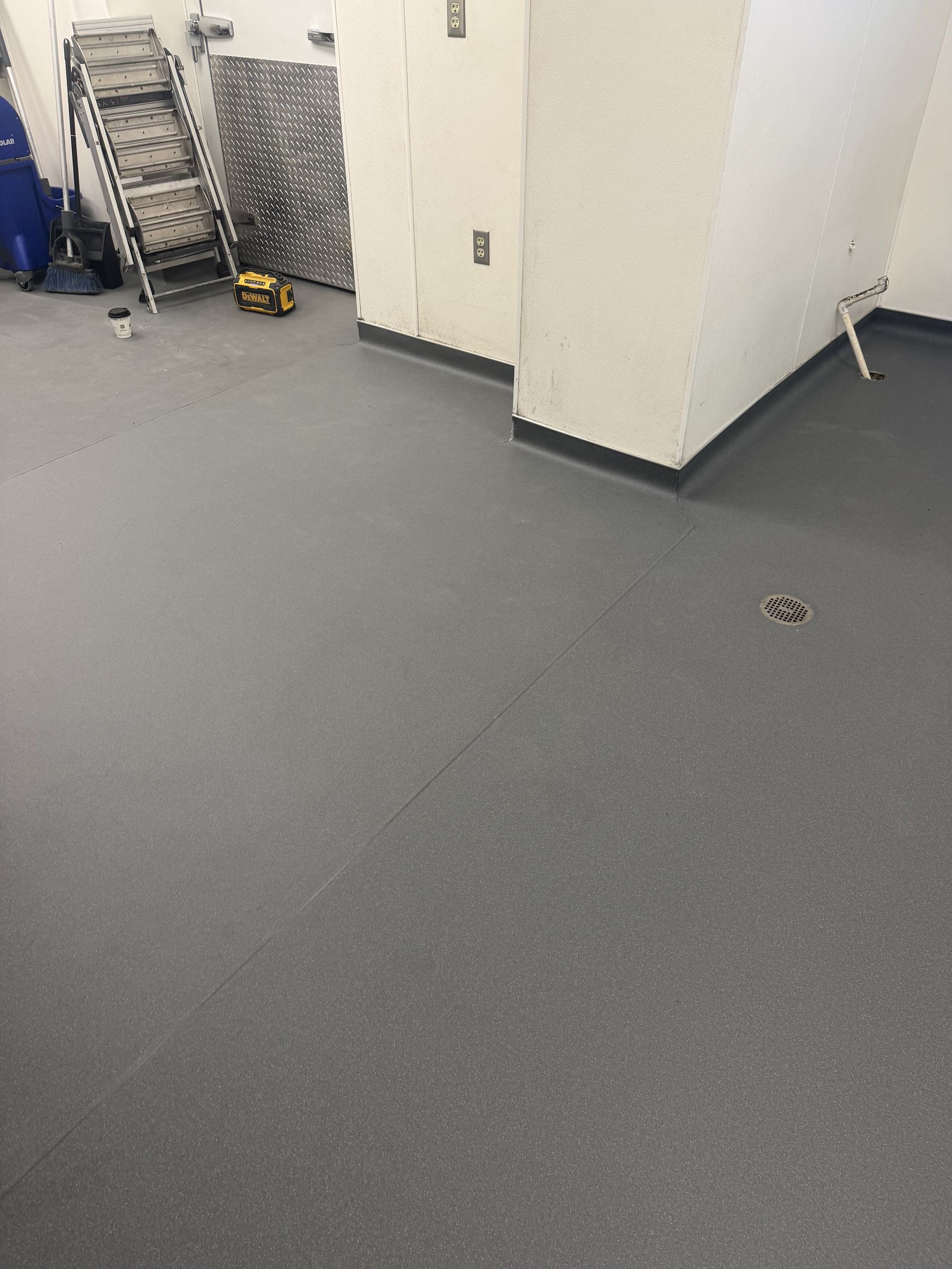 Empty room with gray carpet, white walls, and a metal cart in the corner.