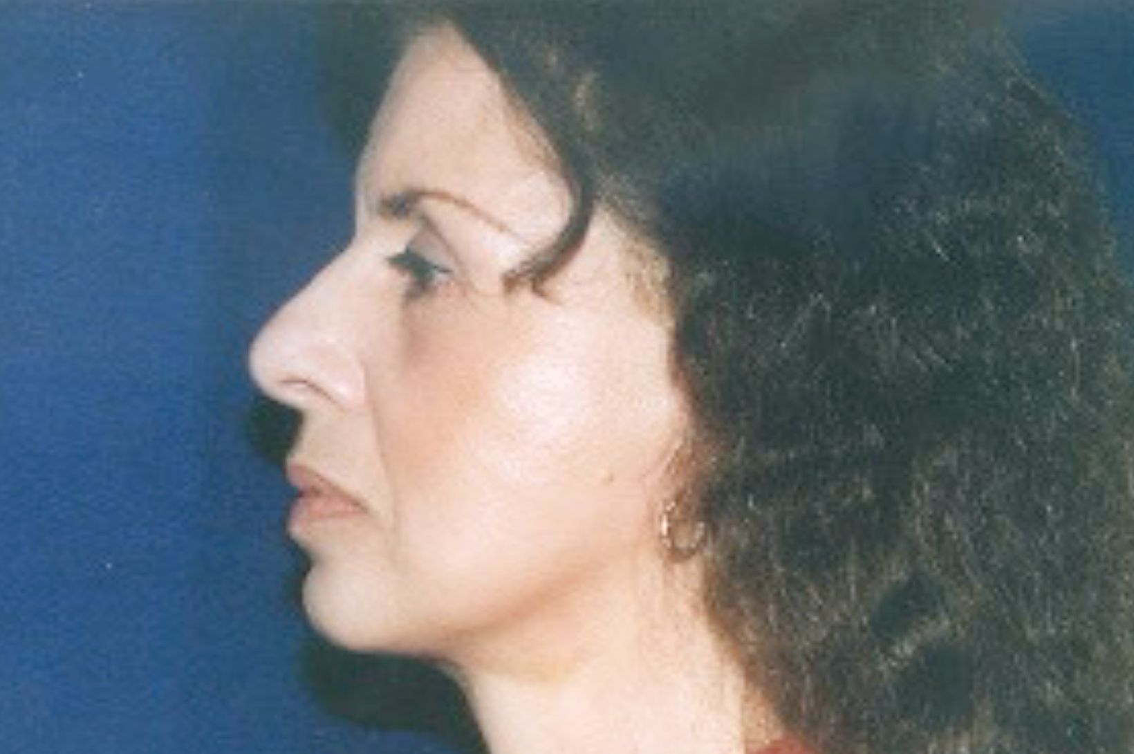 A woman with long hair is wearing a red shirt and earrings