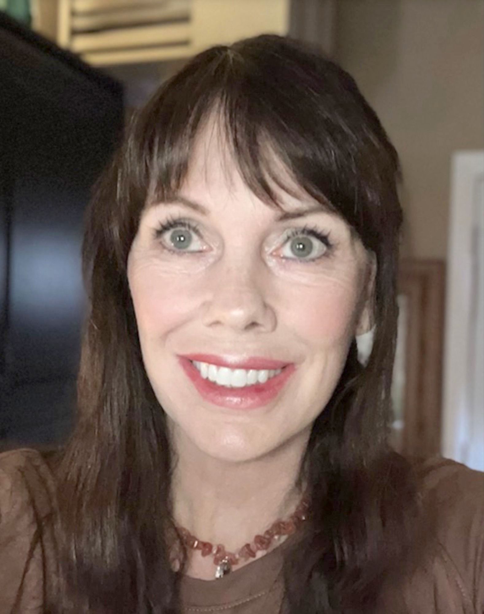 A woman wearing a necklace is smiling for the camera