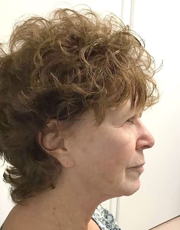 A woman with curly hair is standing in front of a white door