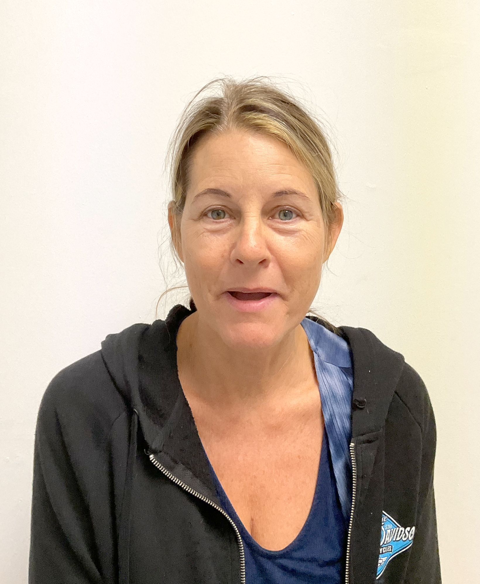 A close up of a woman's face wearing a blue shirt and a necklace
