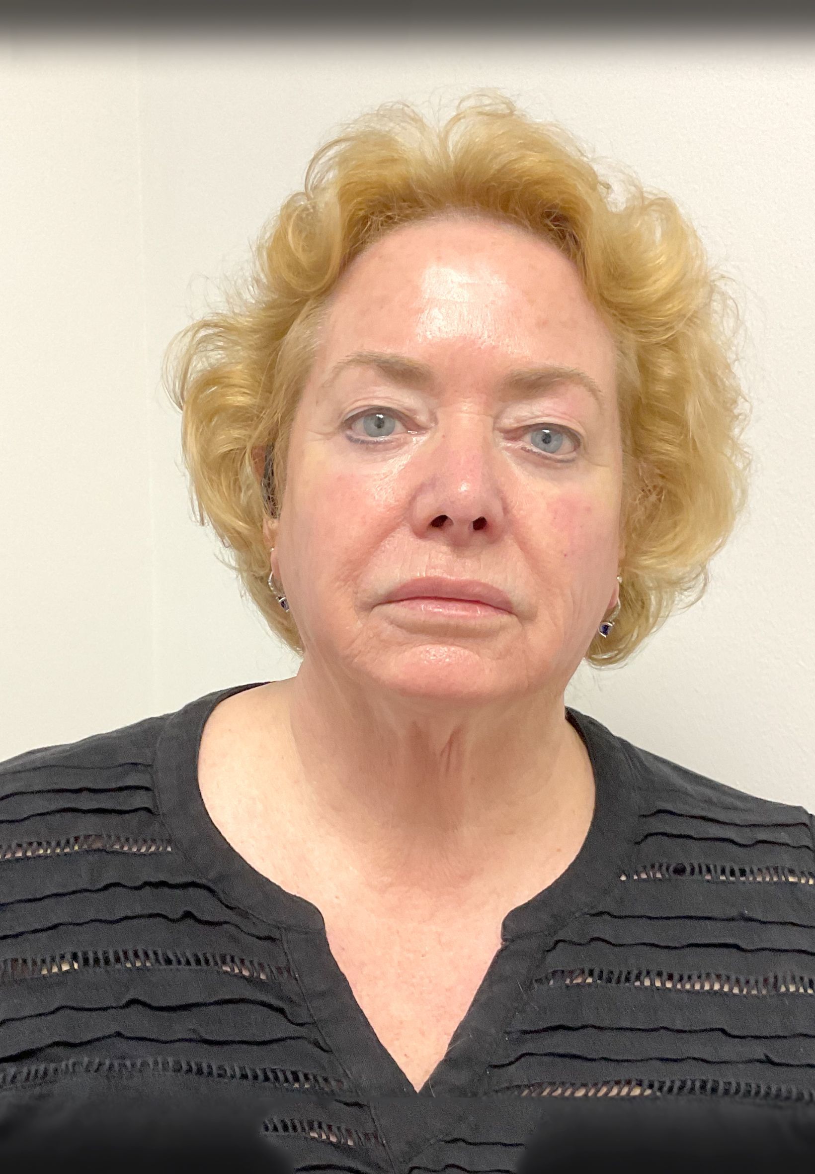 A woman with blonde hair and blue eyes is wearing a black shirt