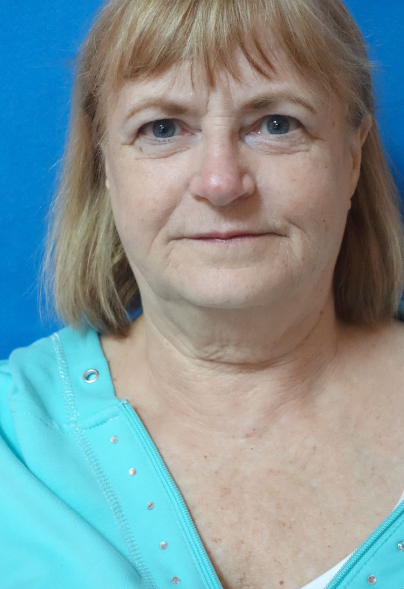 A woman in a blue shirt is looking at the camera