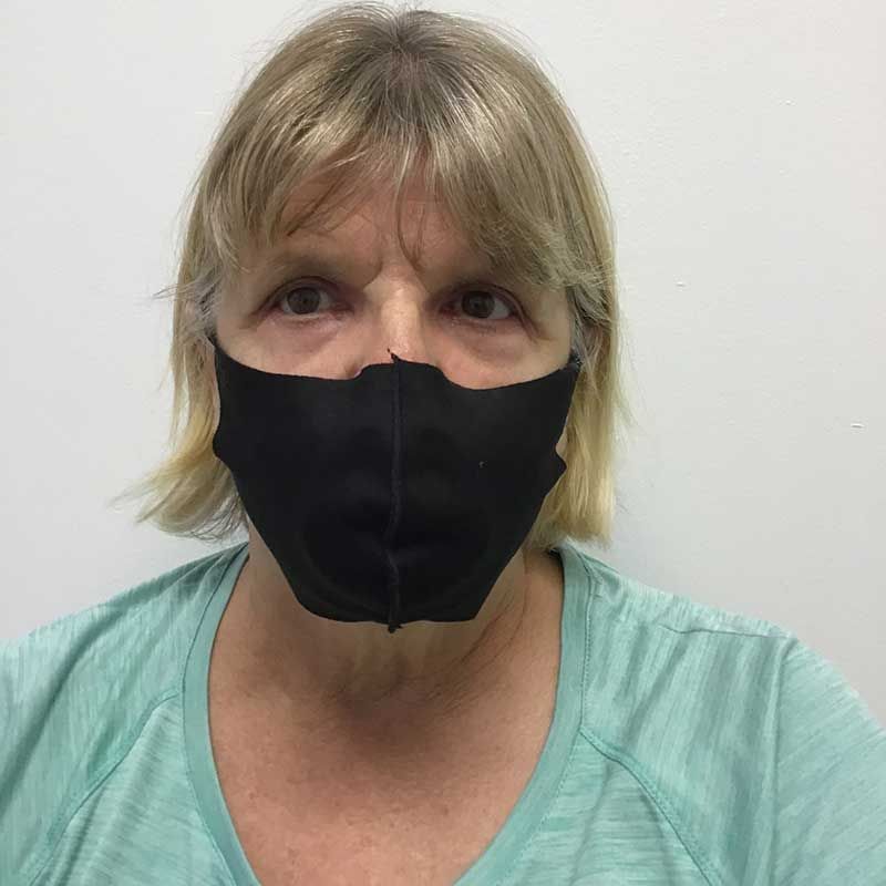 A woman wearing a black face mask and a green shirt